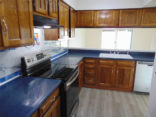 kitchen featuring tasteful backsplash, sink, light hardwood / wood-style flooring, and appliances with stainless steel finishes