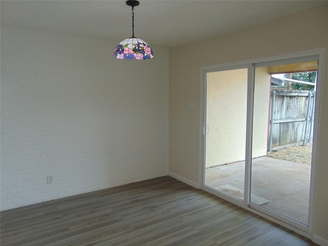 unfurnished room featuring wood-type flooring and brick wall