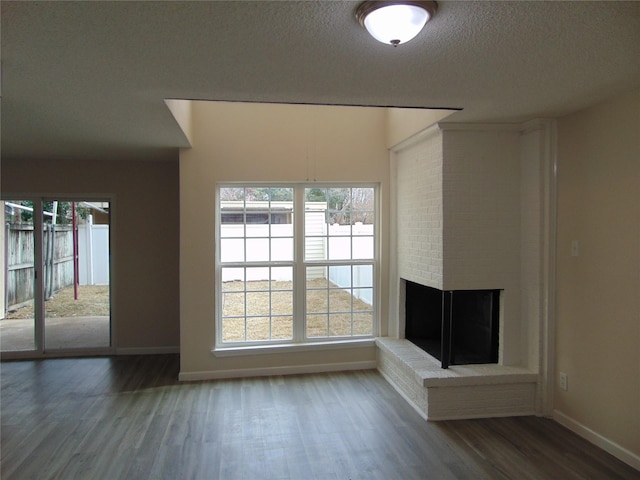 unfurnished living room featuring a brick fireplace, dark wood-type flooring, and a textured ceiling