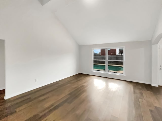 empty room featuring vaulted ceiling and dark hardwood / wood-style floors