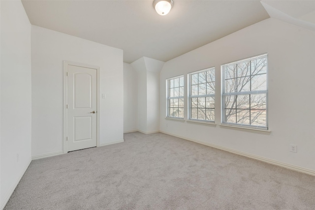 carpeted empty room with lofted ceiling