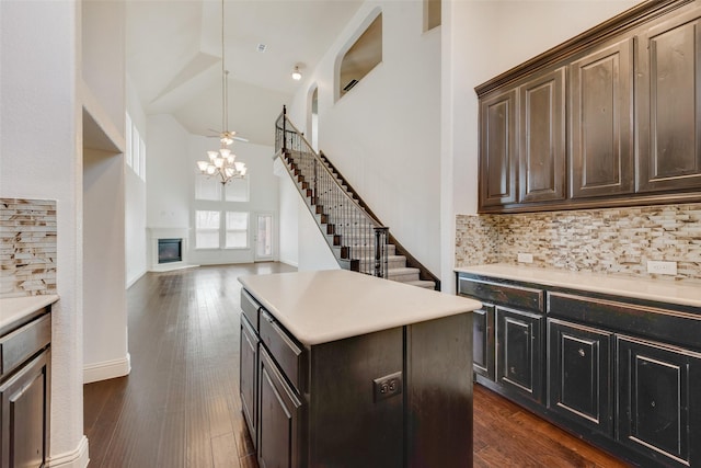 kitchen featuring tasteful backsplash, a kitchen island, dark brown cabinets, and high vaulted ceiling