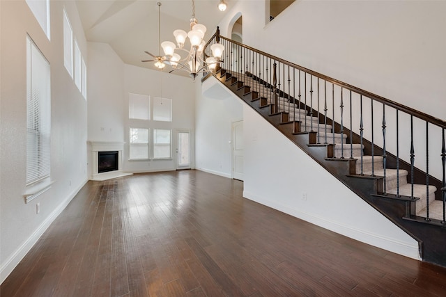 unfurnished living room featuring an inviting chandelier, dark wood-type flooring, and a high ceiling