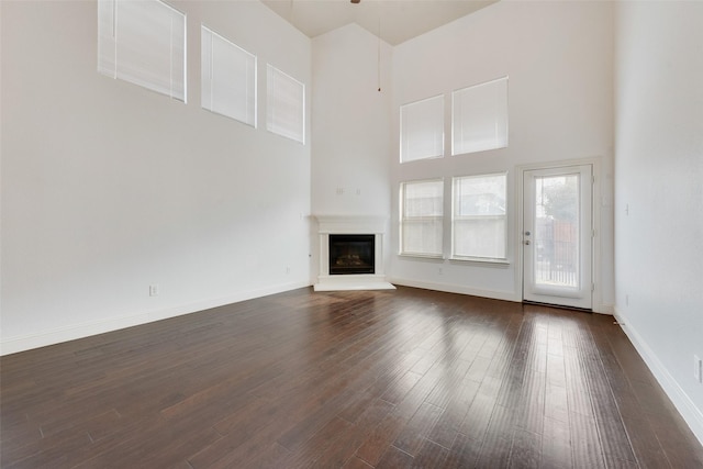 unfurnished living room featuring dark hardwood / wood-style flooring and a towering ceiling