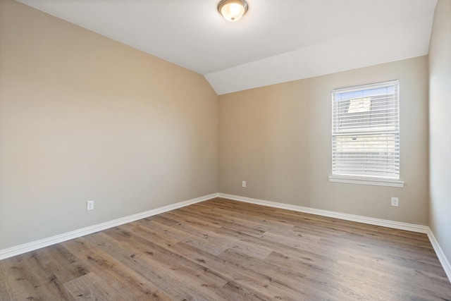 spare room featuring lofted ceiling and light hardwood / wood-style flooring