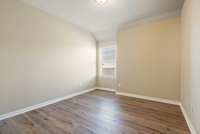 spare room featuring vaulted ceiling and hardwood / wood-style floors