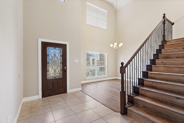 tiled entryway with a chandelier and a high ceiling