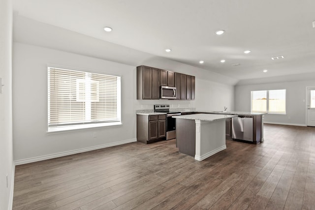 kitchen with dark wood-type flooring, dark brown cabinets, a center island, and appliances with stainless steel finishes