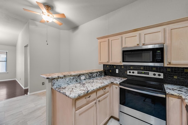 kitchen with light stone counters, light brown cabinets, kitchen peninsula, stainless steel appliances, and decorative backsplash