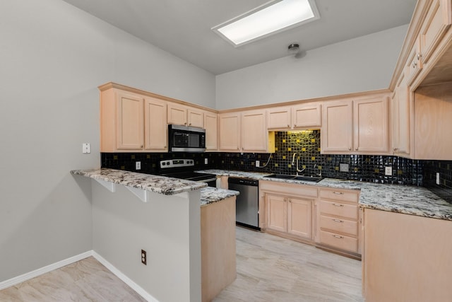 kitchen with light stone counters, sink, stainless steel appliances, and kitchen peninsula