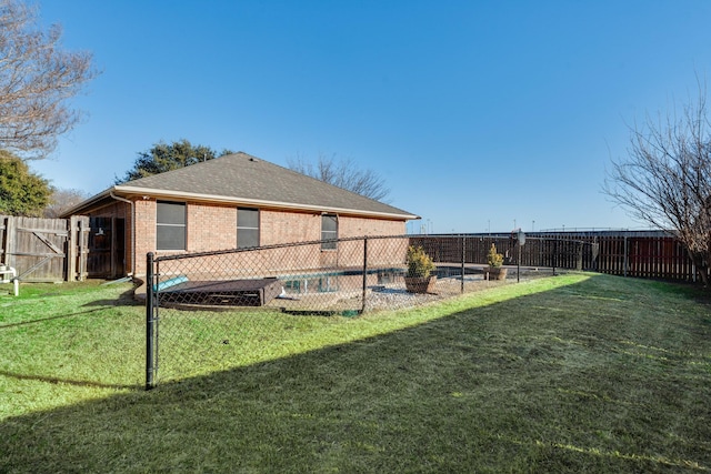 rear view of house featuring a fenced in pool and a lawn