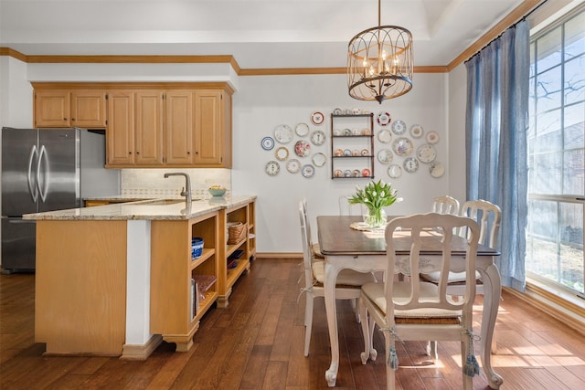 kitchen with dark hardwood / wood-style floors, stainless steel refrigerator, decorative light fixtures, sink, and light stone countertops