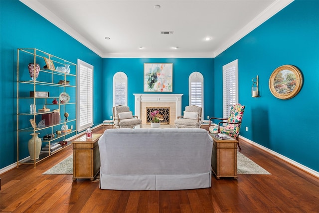 living room with a tile fireplace, wood-type flooring, and ornamental molding