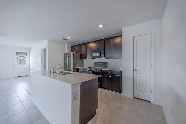 kitchen featuring an island with sink, dark brown cabinets, sink, and black appliances