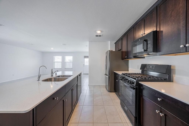 kitchen with sink, dark brown cabinets, light tile patterned floors, a kitchen island with sink, and black appliances