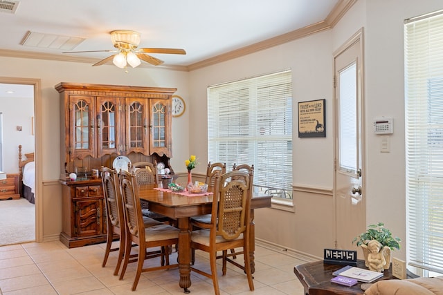 tiled dining space featuring crown molding and ceiling fan