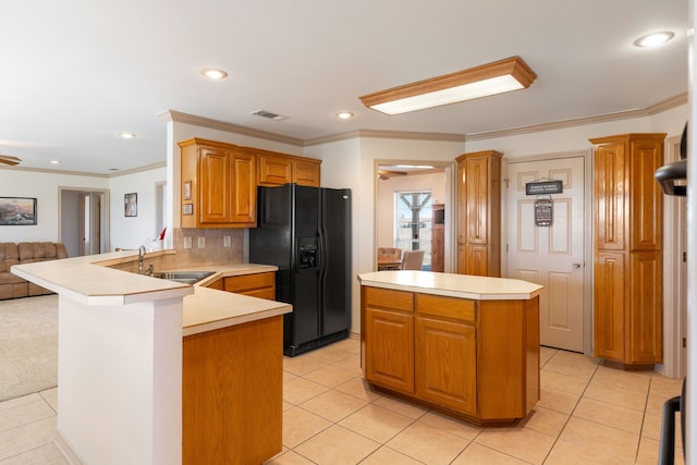 kitchen with sink, light tile patterned floors, ornamental molding, black fridge with ice dispenser, and kitchen peninsula