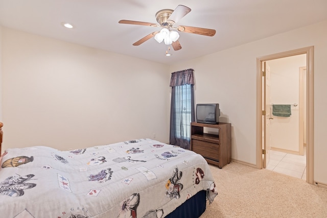 bedroom featuring connected bathroom, light colored carpet, and ceiling fan