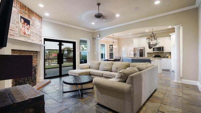 living room featuring crown molding, a fireplace, decorative columns, and ceiling fan