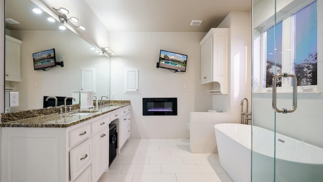 bathroom featuring tile patterned floors, toilet, vanity, a tile fireplace, and a washtub