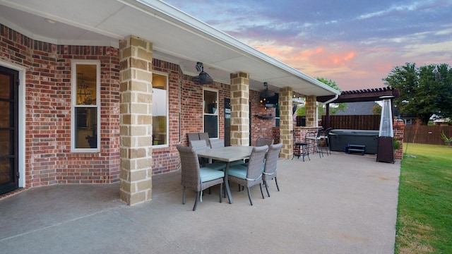 patio terrace at dusk featuring a pergola and a hot tub