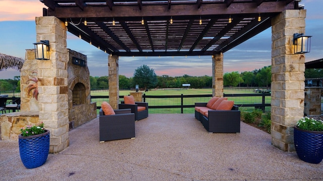 patio terrace at dusk featuring a pergola, a lawn, and an outdoor living space with a fireplace