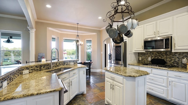 kitchen with an island with sink, appliances with stainless steel finishes, white cabinets, and decorative backsplash