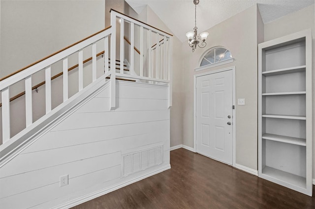 entryway with dark hardwood / wood-style flooring, vaulted ceiling, a textured ceiling, and a notable chandelier