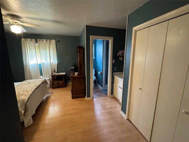 bedroom with light wood finished floors, ceiling fan, and connected bathroom
