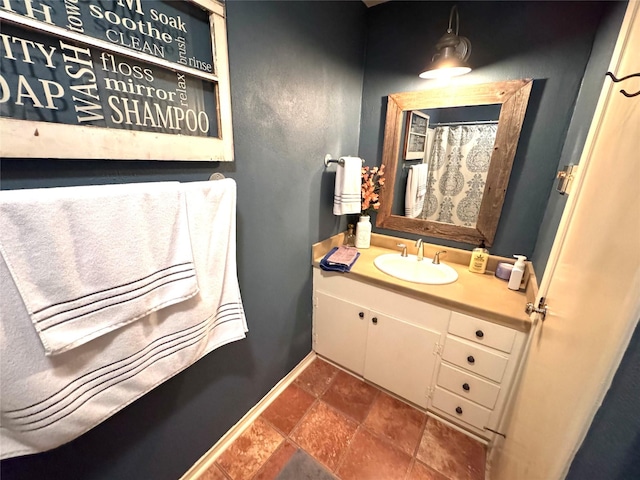 bathroom with stone finish floor, vanity, and baseboards
