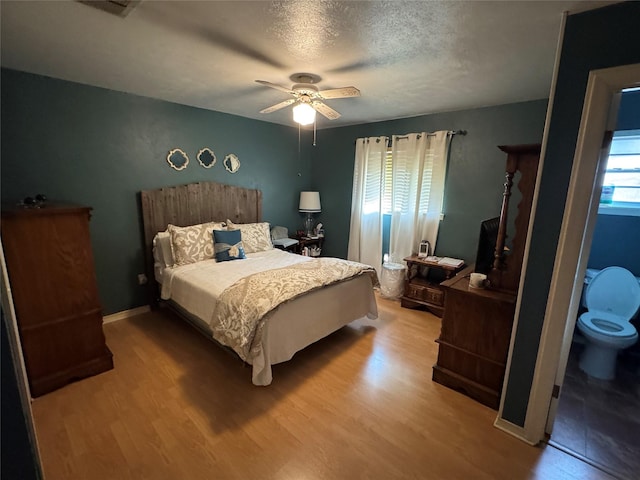 bedroom featuring baseboards, visible vents, a ceiling fan, wood finished floors, and a textured ceiling