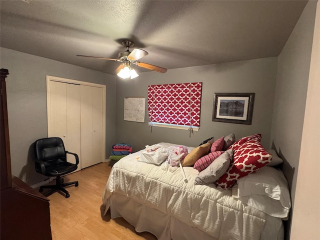 bedroom with a ceiling fan, a closet, light wood-style flooring, and a textured ceiling