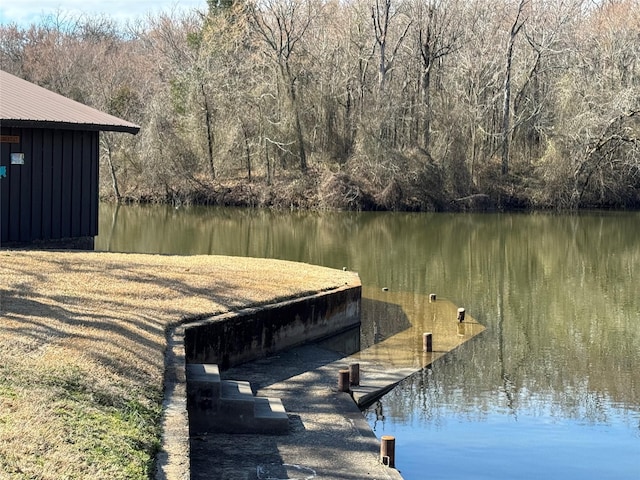 view of dock with a water view and a forest view