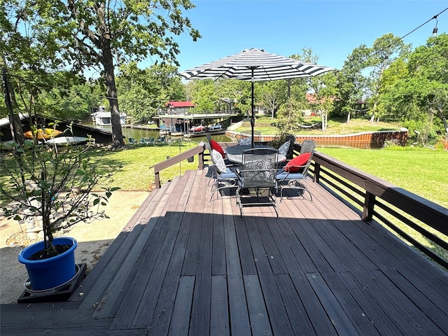 wooden terrace with outdoor dining area and a lawn