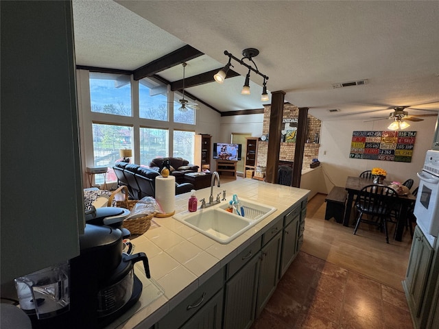 kitchen with tile counters, a ceiling fan, visible vents, white oven, and a sink
