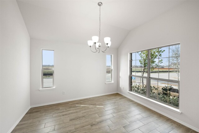 unfurnished room featuring lofted ceiling, a healthy amount of sunlight, hardwood / wood-style floors, and an inviting chandelier