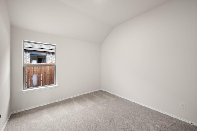 carpeted empty room with vaulted ceiling