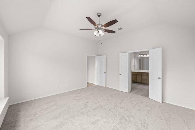 unfurnished bedroom featuring connected bathroom, light carpet, lofted ceiling, and ceiling fan