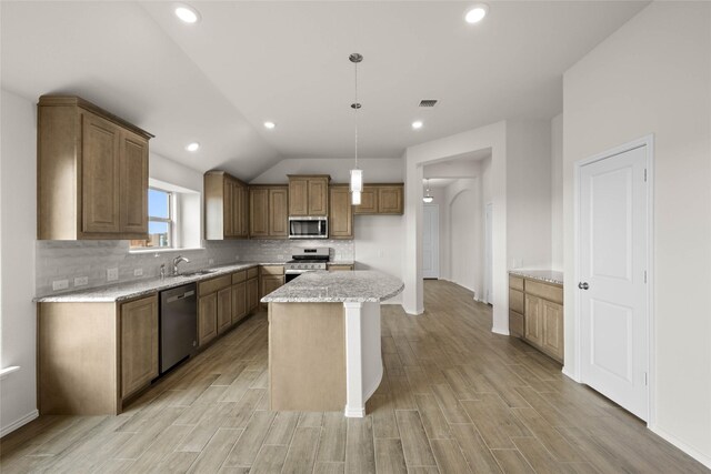 kitchen featuring appliances with stainless steel finishes, decorative light fixtures, tasteful backsplash, a center island, and light stone counters