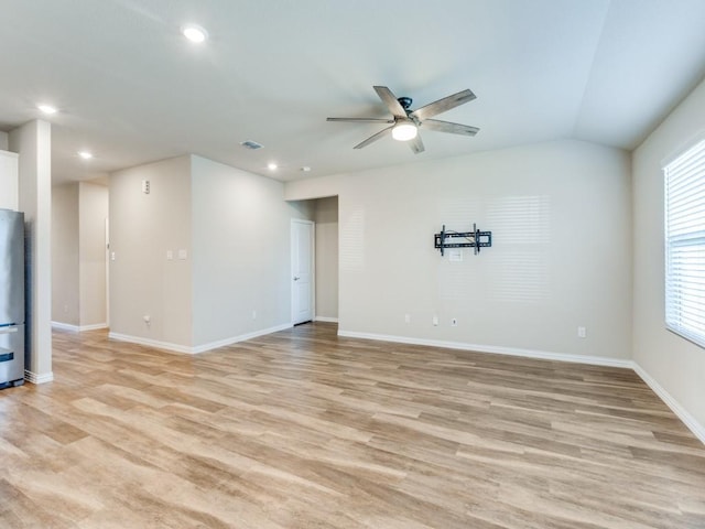 empty room with lofted ceiling, ceiling fan, and light hardwood / wood-style flooring