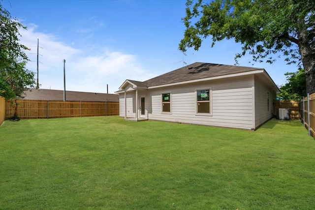 rear view of property featuring a yard and central AC