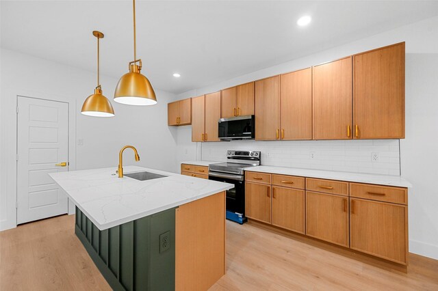 kitchen featuring a kitchen island with sink, sink, backsplash, and stainless steel appliances