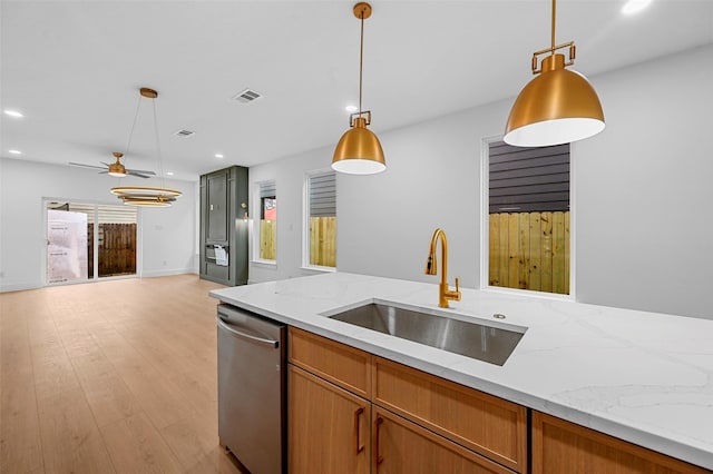 kitchen with sink, stainless steel dishwasher, hanging light fixtures, and light stone countertops