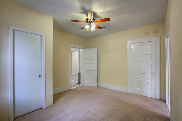 unfurnished bedroom featuring a textured ceiling, light colored carpet, and ceiling fan