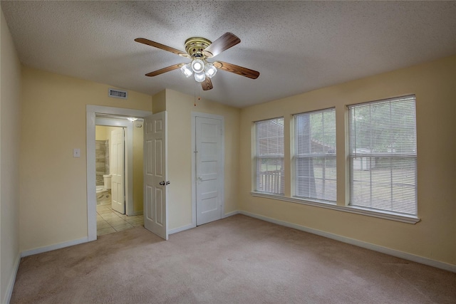 spare room with ceiling fan, light carpet, and a textured ceiling