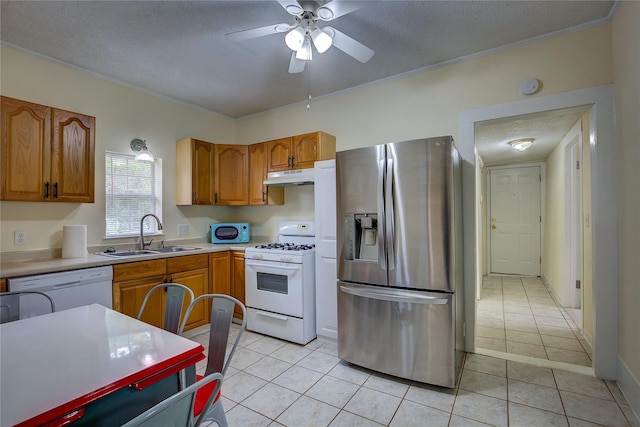 kitchen with white appliances, sink, a textured ceiling, and light tile patterned floors