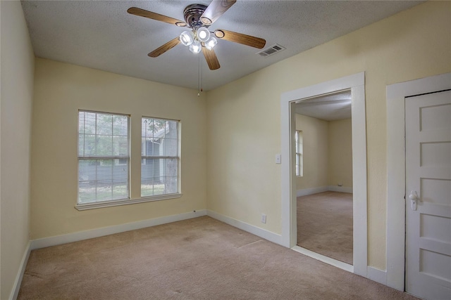 spare room featuring light carpet, a textured ceiling, and ceiling fan