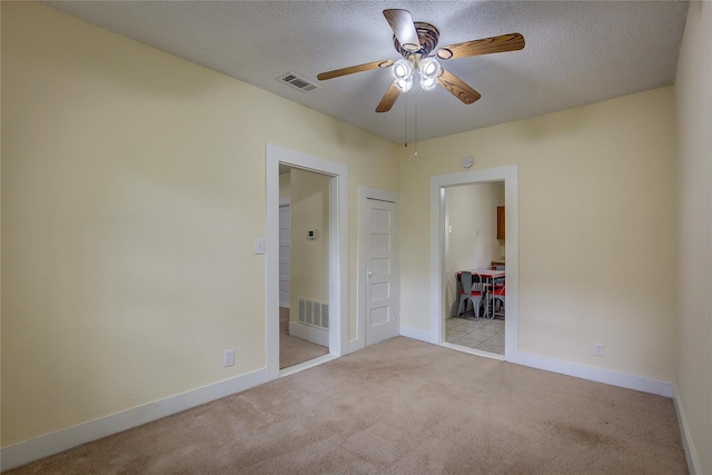 unfurnished bedroom with a textured ceiling, light colored carpet, a closet, and ceiling fan