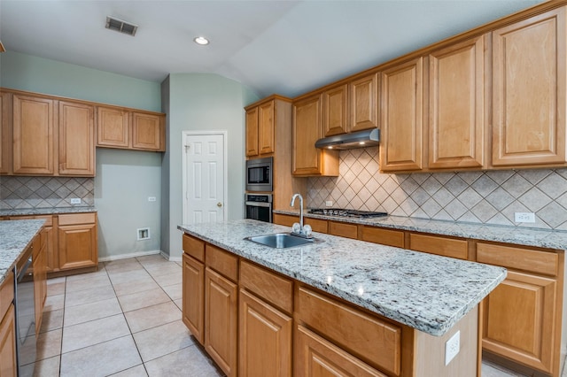 kitchen with light tile patterned flooring, appliances with stainless steel finishes, sink, a center island, and light stone countertops