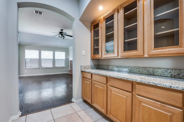 kitchen with light stone counters, ceiling fan, and light tile patterned floors